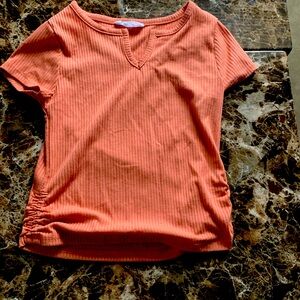 A pinky orange top with a V-neck and scrunches on the sides